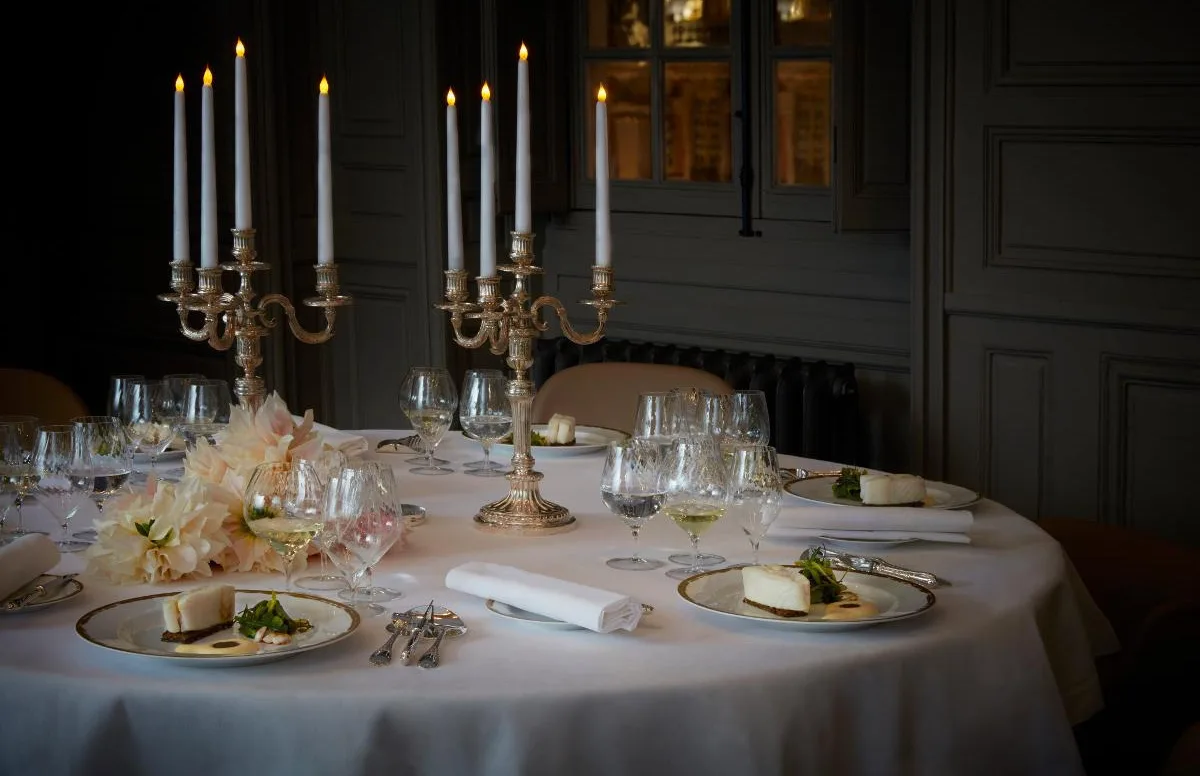 Table dressée aux chandelles, verres et couverts alignés