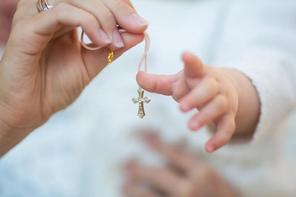 Croix de baptême tenue au-dessus d’un enfant
